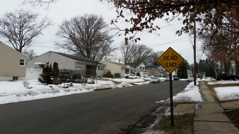 dead end street in the winter, snow on the ground, yellow dead end sign