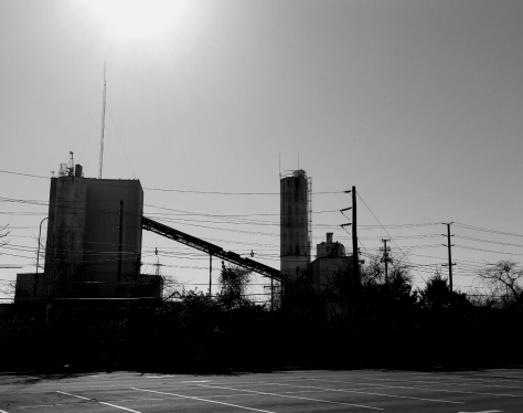 industrial structures next to parking lot, black and white