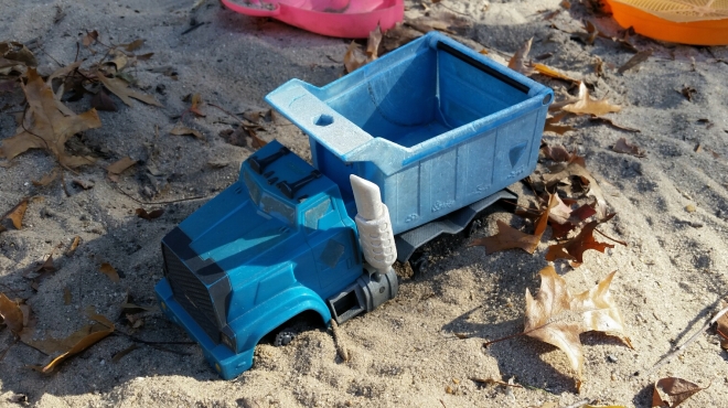 Blue toy truck in playground sandbox